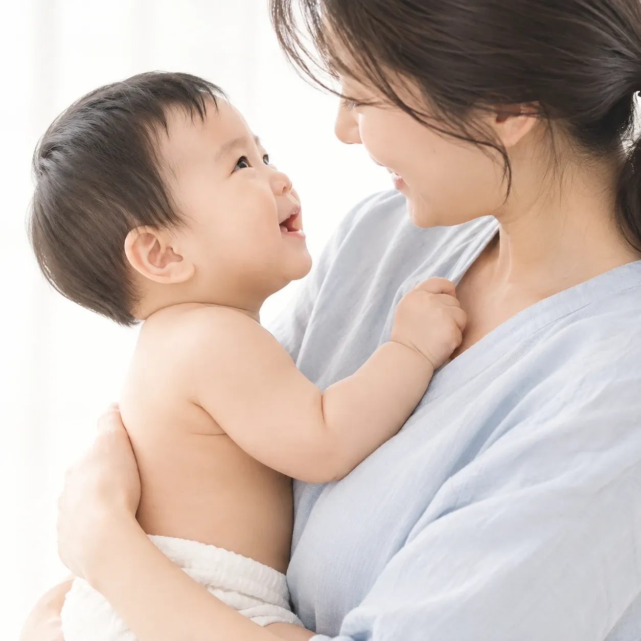 엄마가 아기를 품에 안고 마주 보며 웃는 모습